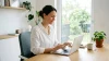 Femme souriante travaillant sur laptop à son bureau