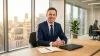 Homme d'affaires souriant à son bureau avec vue urbaine