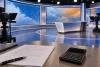 Un studio météo vide avec des écrans abstraits, un contrat flouté et une calculatrice éteinte